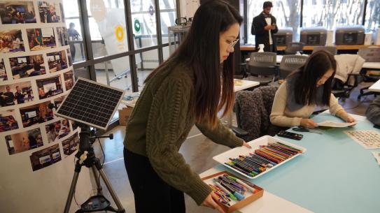 student placing tray of markers on table