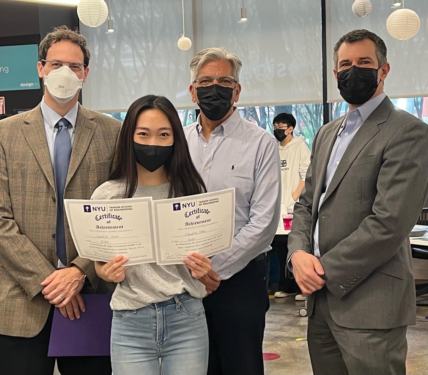 student holding certificate alongside capstone judges