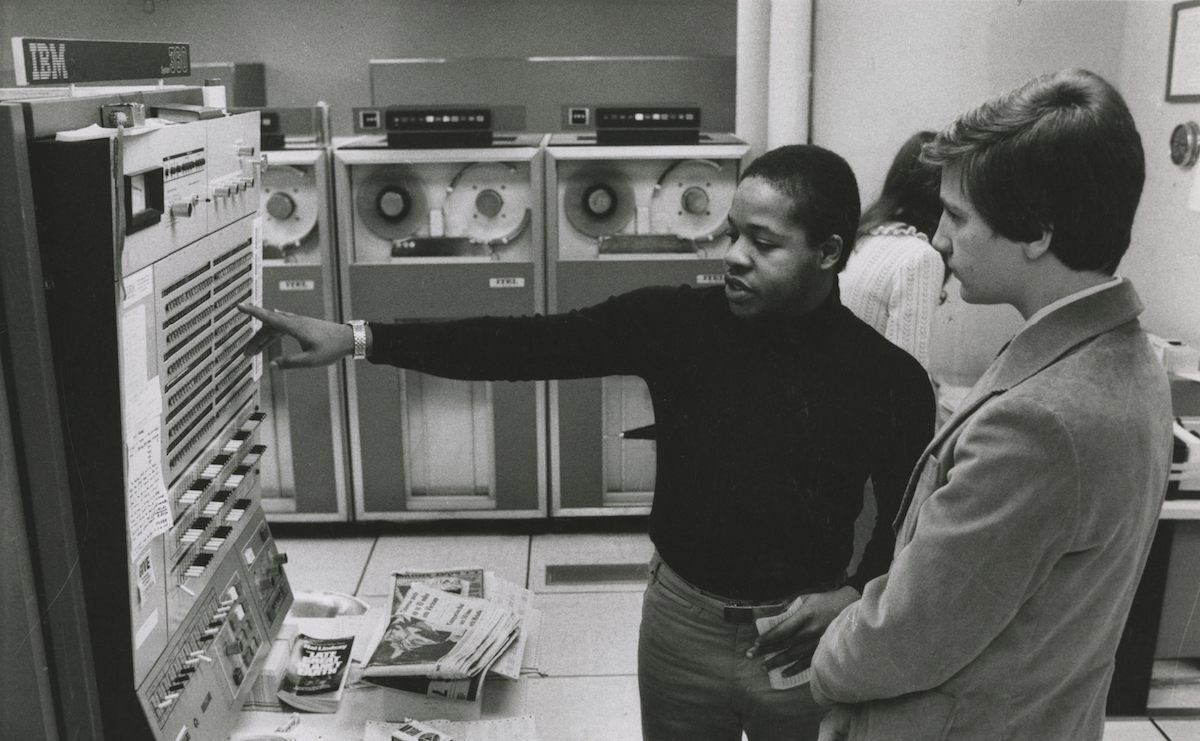 2 men looking at large data processing unit