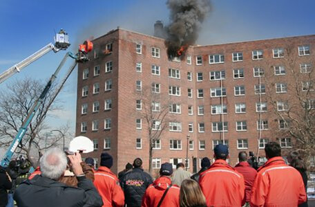 people watching smoke coming out of the top floor of 7 story building